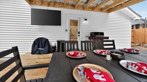 A covered patio with a table set for dining, a ceiling fan, and a TV mounted on the wall. - Tide Twins 1 | Sleeps 10 | Pet Friendly | 1.9 Miles to Bryant-Denny Stadium (Tuscaloosa)