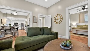 A spacious living area with a green sofa, a round coffee table, and a dining area with a chandelier. - Tide Twins 1 | Sleeps 10 | Pet Friendly | 1.9 Miles to Bryant-Denny Stadium (Tuscaloosa)
