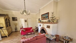 Una sala de estar con chimenea, un sofá rojo, una mesa de comedor y una araña.