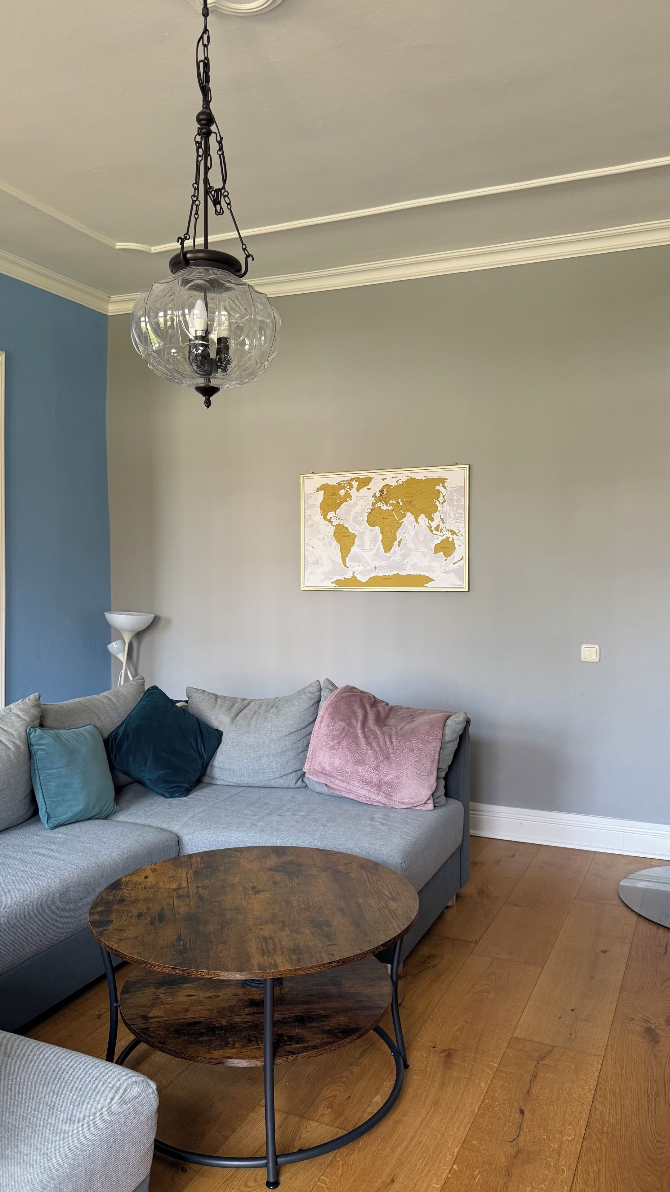 A living room with a sectional sofa, a round coffee table, a hanging globe map, and a chandelier.