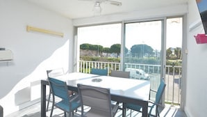 Een balkon met een tafel en stoelen, een plafondventilator en uitzicht op de straat.