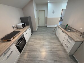 Eine moderne Küche mit Einbauherd, Mikrowelle und Geschirrspüler, Holzarbeitsplatten und Fliesenboden.