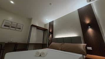 A hotel room with a bed, bedside table, and a wall-mounted air conditioner.
