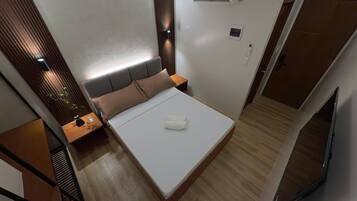 Habitación de hotel moderna con cama, mesita de noche y televisor montado en la pared.