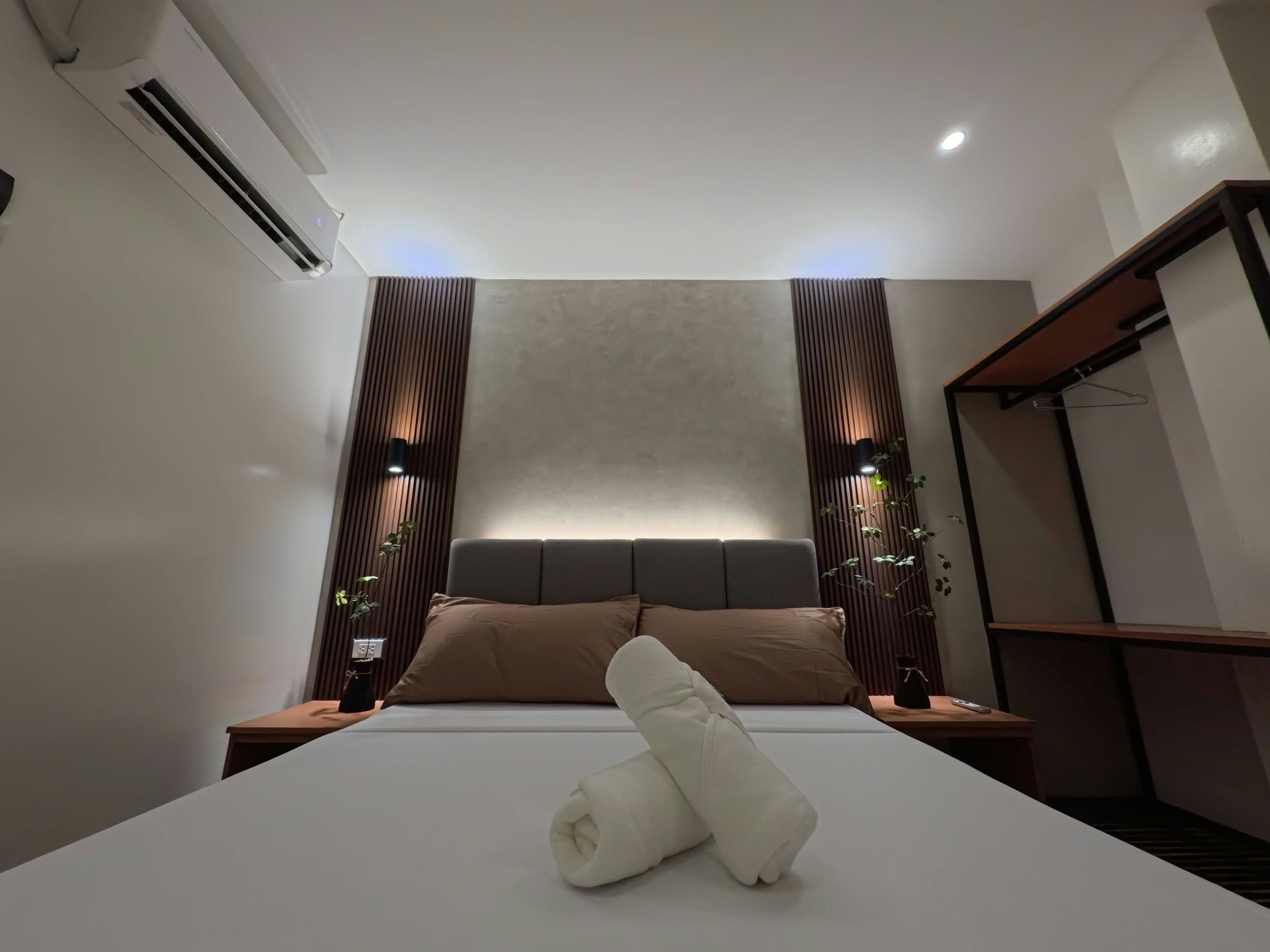 A modern hotel room with a large bed, a headboard, and a bedside table.