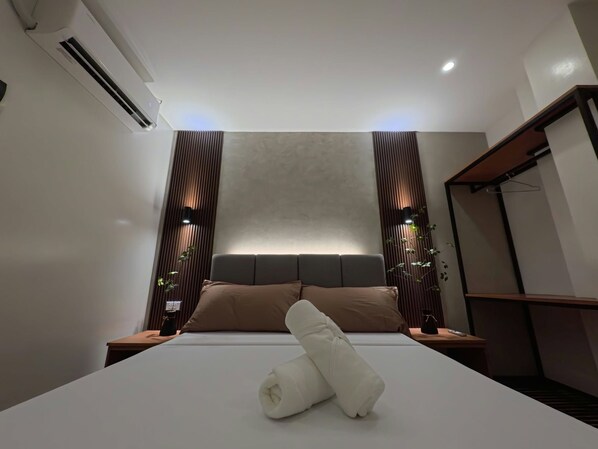 A modern hotel room with a large bed, a headboard, and a bedside table. - Penthouse 6500 Hotel (Tacloban)