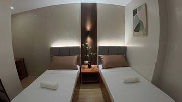 Quarto de hotel com duas camas, luminária central e uma obra de arte pendurada na parede.