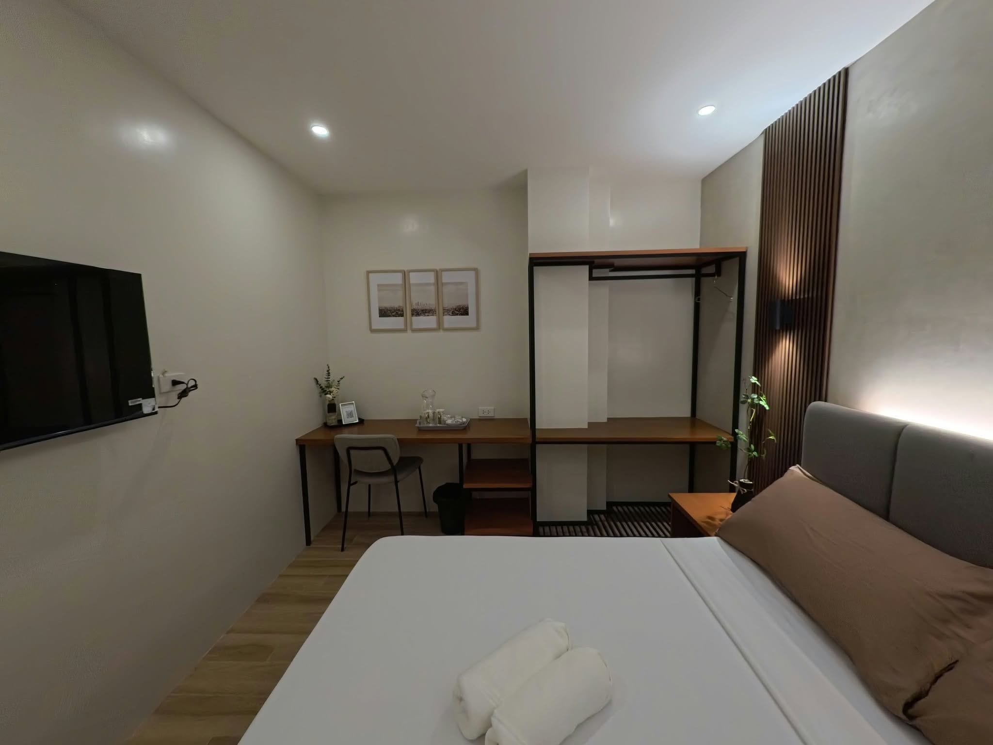 A hotel room with a bed, a desk, a chair, a TV, and a window with blinds.