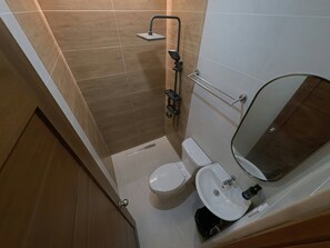 Un baño con inodoro, lavamanos, espejo y ducha.