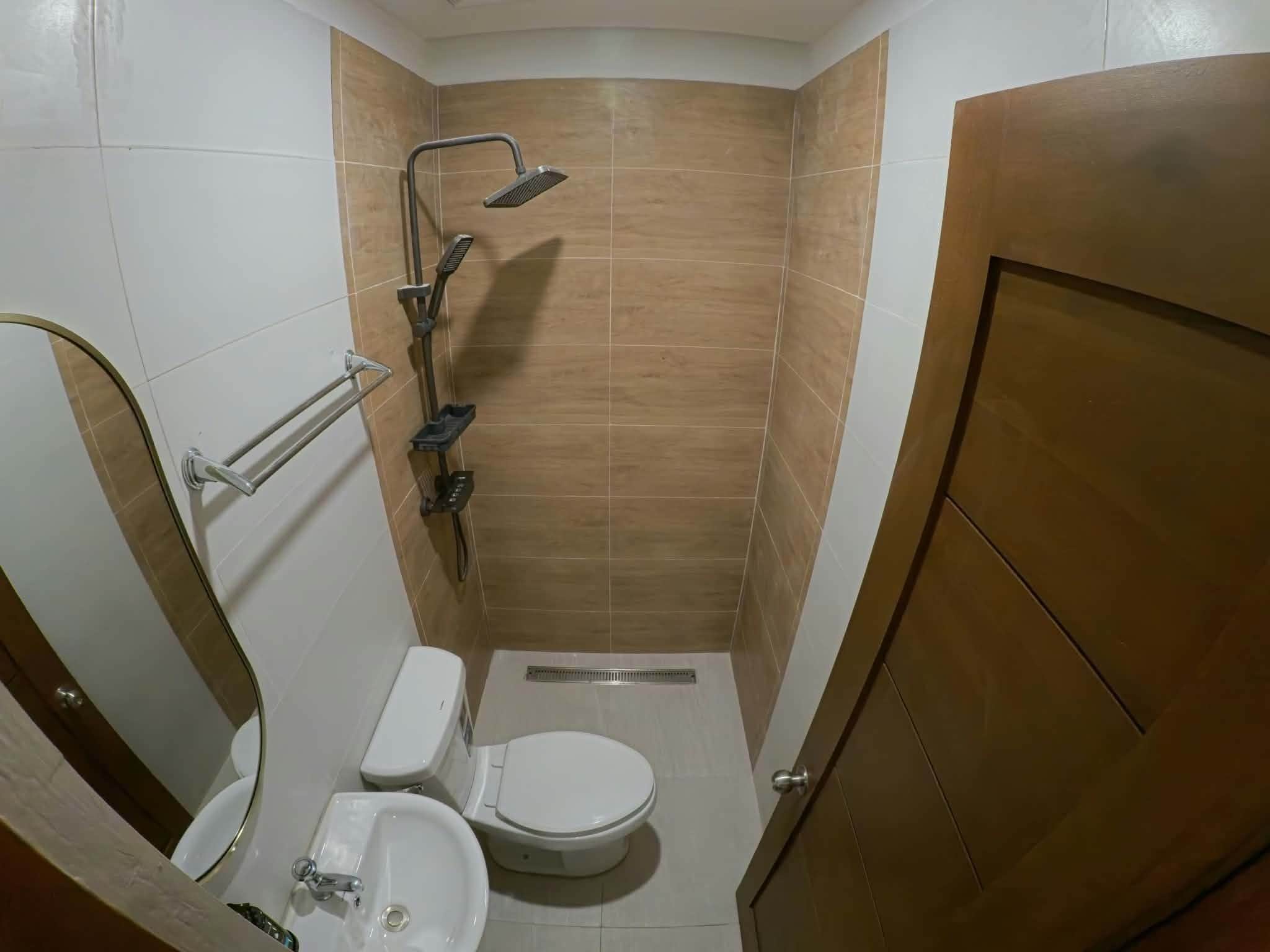 A small bathroom with a toilet, sink, and shower.