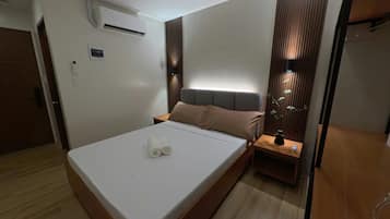 Una habitación de hotel moderna con cama, mesita de noche y aire acondicionado.