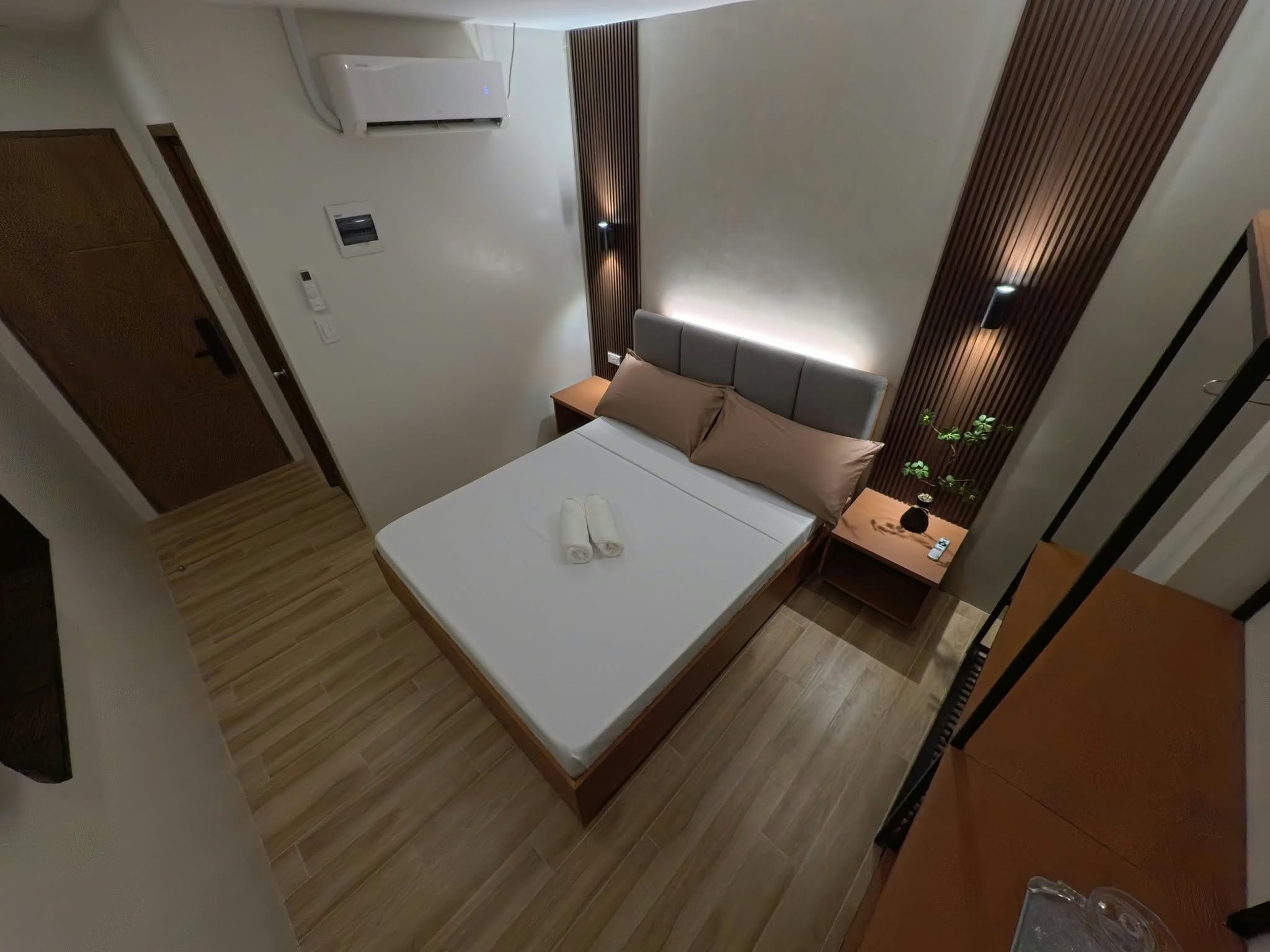 Una habitación de hotel con cama, mesita de noche y aire acondicionado.