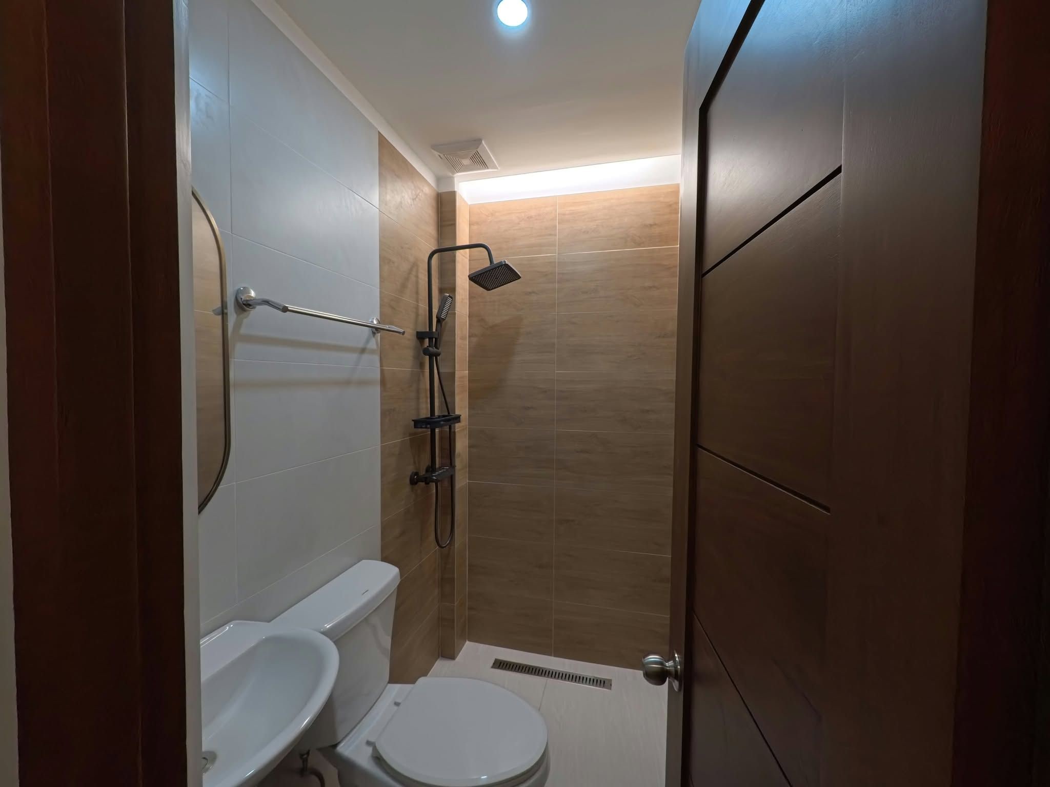 A compact bathroom with a toilet, a shower, and a sink.