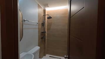 A compact bathroom with a toilet, a shower, and a sink.