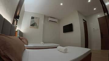 A modern hotel room with two beds, a flat-screen TV, an air conditioning unit, and a wall-mounted artwork.