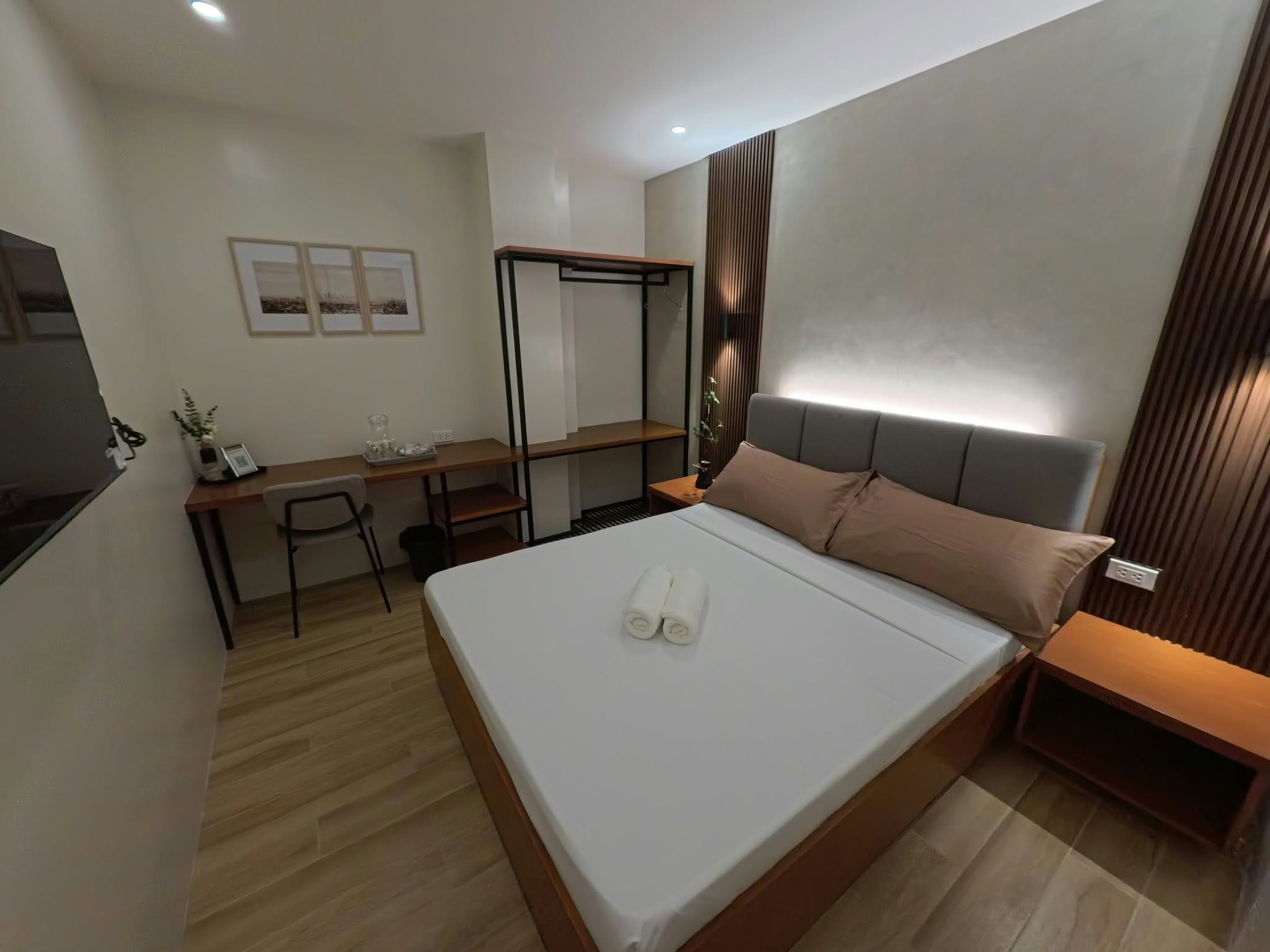 A modern hotel room with a bed, desk, and seating area.