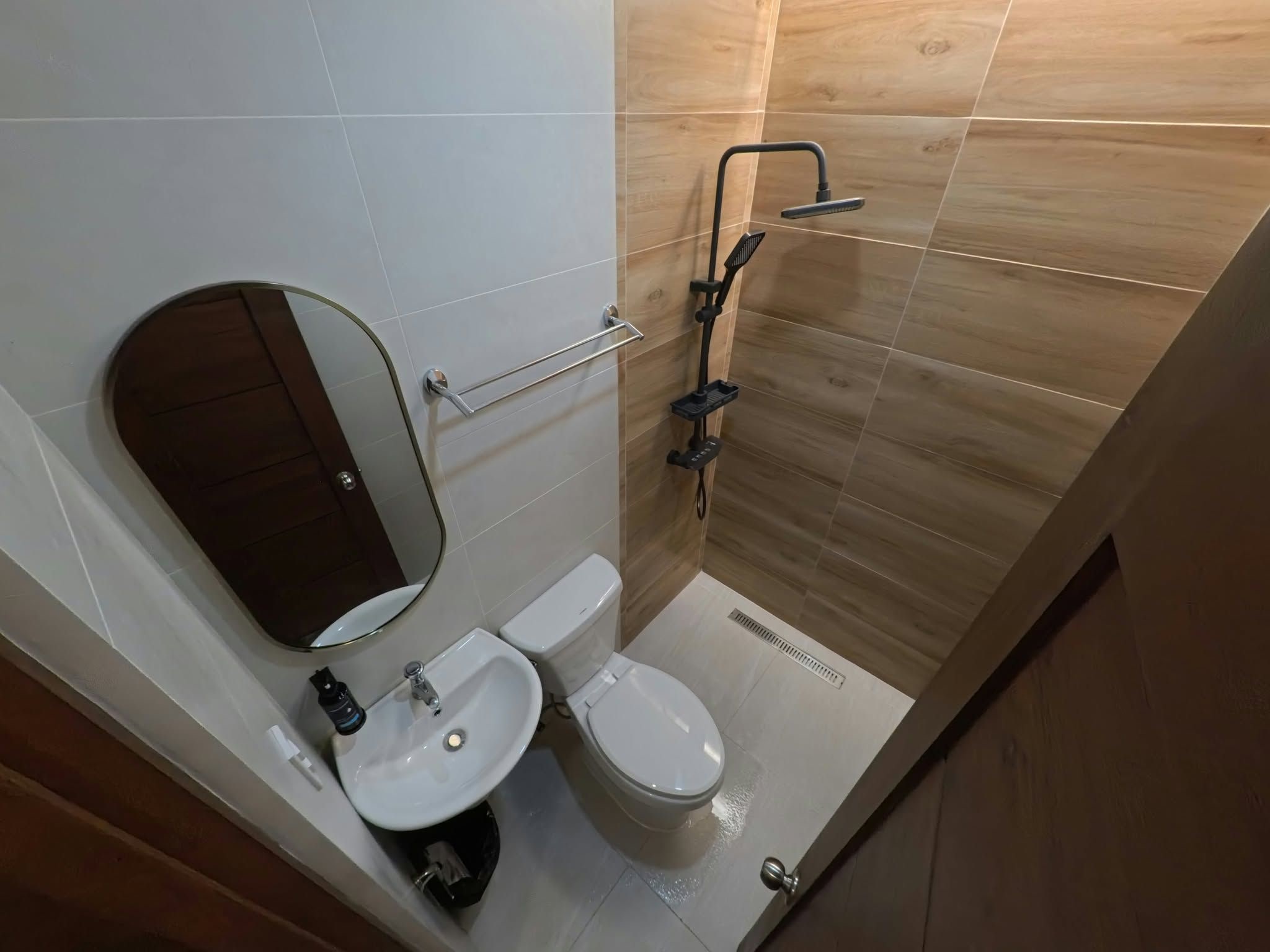 A bathroom with a toilet, sink, mirror, and shower.