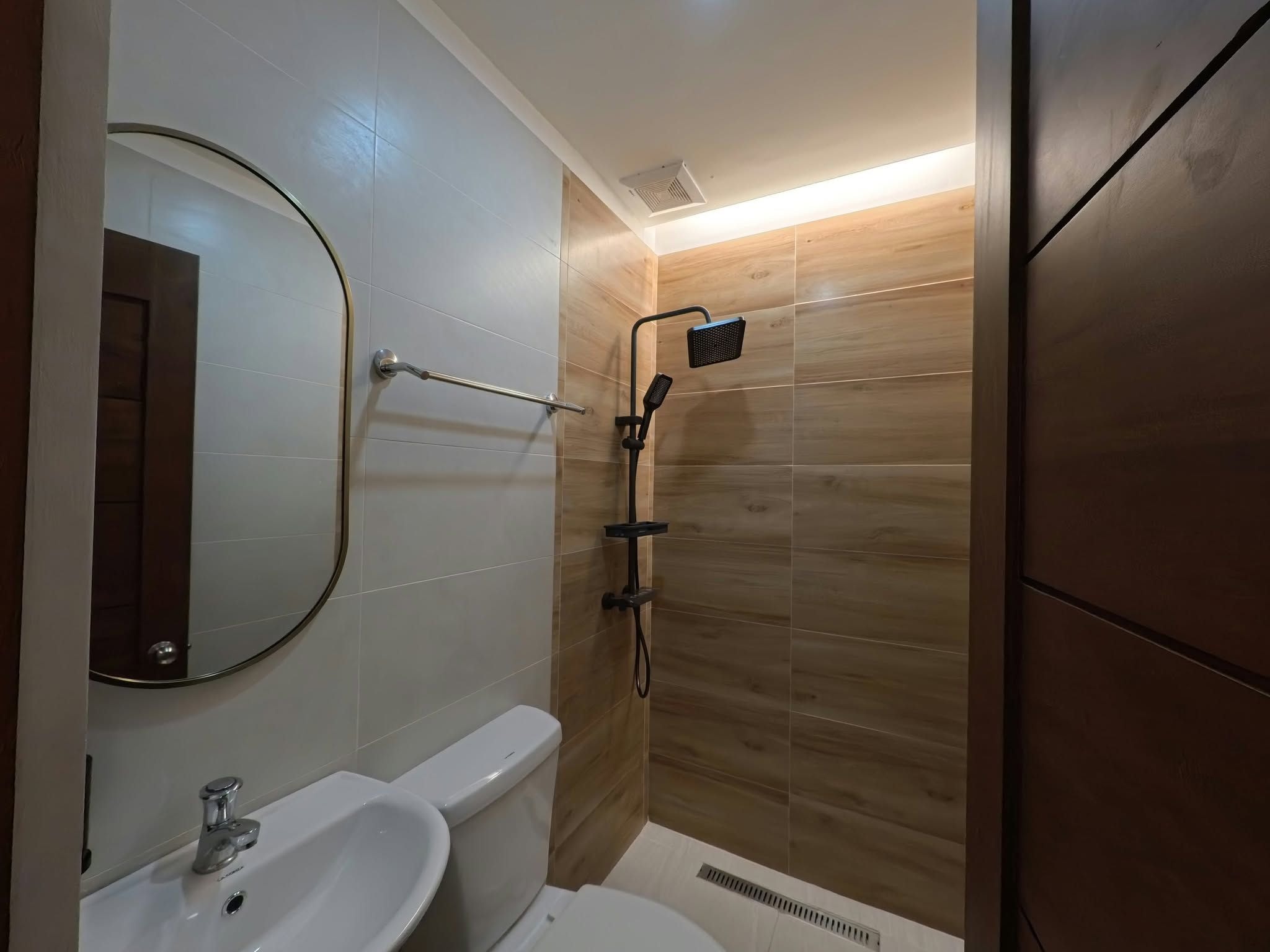 Een badkamer met toilet, wastafel, spiegel en douche.