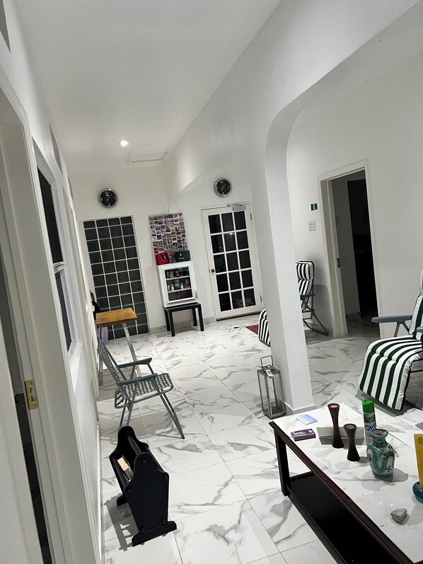 Ein geräumiger Raum mit Marmorboden, einem Esstisch, Stühlen, einem kleinen Tisch mit einer Vase und einer Uhr an der Wand.