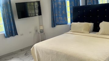 Une chambre à coucher avec un lit, un téléviseur à écran plat, une fenêtre avec des rideaux et un sol en marbre.