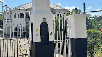 A gated entrance with a CCTV warning sign, numbered gates, and a building with a tiled roof in the background.