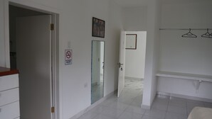 A hotel room with a bathroom, a wardrobe, and a door leading to another room.