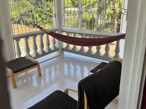 Ein Balkon mit einer Hängematte, zwei Stühlen und Blick ins Grüne.