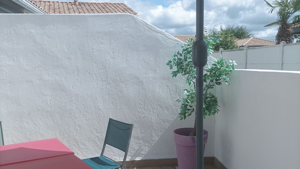 A patio with a table and chair, a potted plant, and a white wall. - House on the Arcachon Bay with Air Conditioning (Gujan-Mestras)