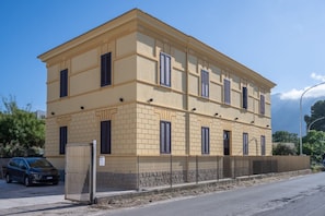 Ein mehrstöckiges Gebäude mit einer symmetrischen Fassade, gekennzeichnet durch gleichmäßig verteilte Fenster und einen zentralen Eingang.