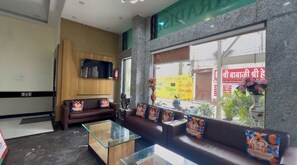 A hotel lobby with a sofa, a glass coffee table, and a television on the wall. - JMC HOTEL SOTEL INDORE (Indore)
