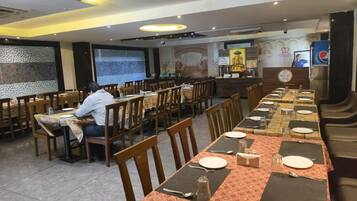 Un restaurante con varias mesas, sillas y una persona sentada en una de ellas.