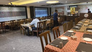 A restaurant with multiple dining tables, chairs, and a counter area. - JMC HOTEL SOTEL INDORE (Indore)