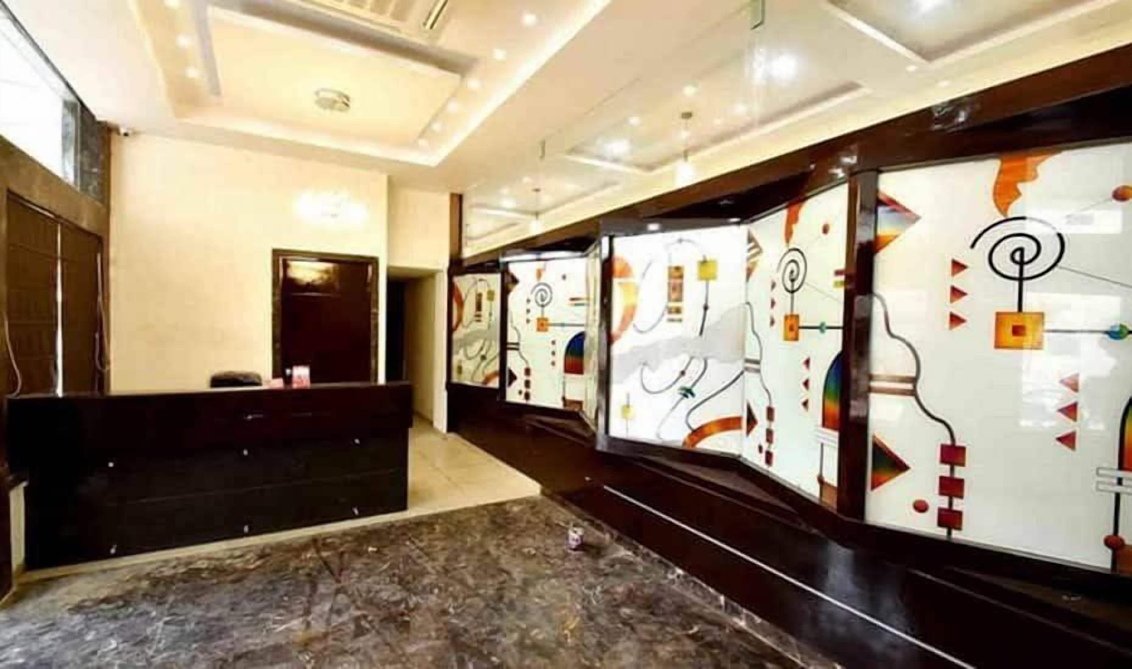 A hotel reception area with a marble floor, a reception desk, and decorative glass panels with abstract designs.