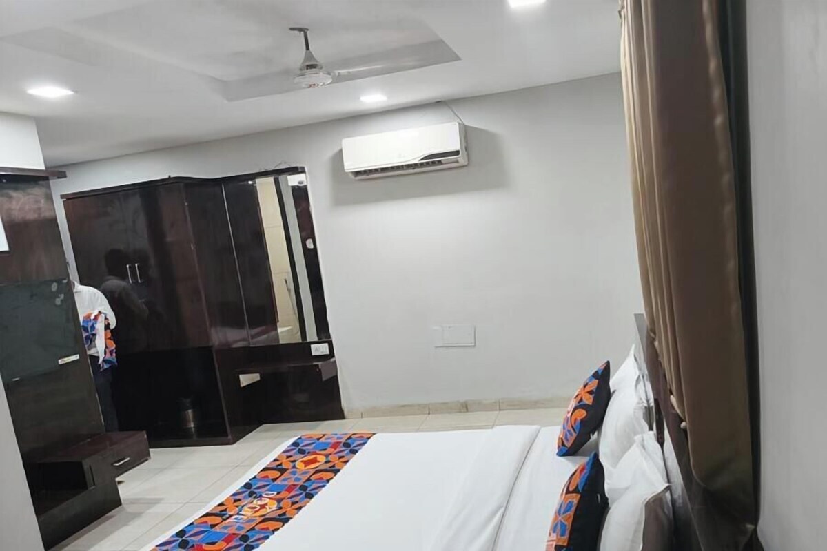 A hotel room with a bed, a wardrobe, an air conditioning unit, and a ceiling fan.