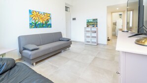 Ein Wohnzimmer mit grauem Sofa, einem weißen Schrank und Bildern an den Wänden.