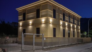 Ein mehrstöckiges Gebäude mit einer symmetrischen Fassade, gleichmäßig verteilten Fenstern und einem Eingangstor.