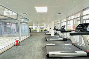 A gym with treadmills, exercise equipment, and large windows. - Bloomfields 1BR in Oasis Masdar  (Abu Dhabi)