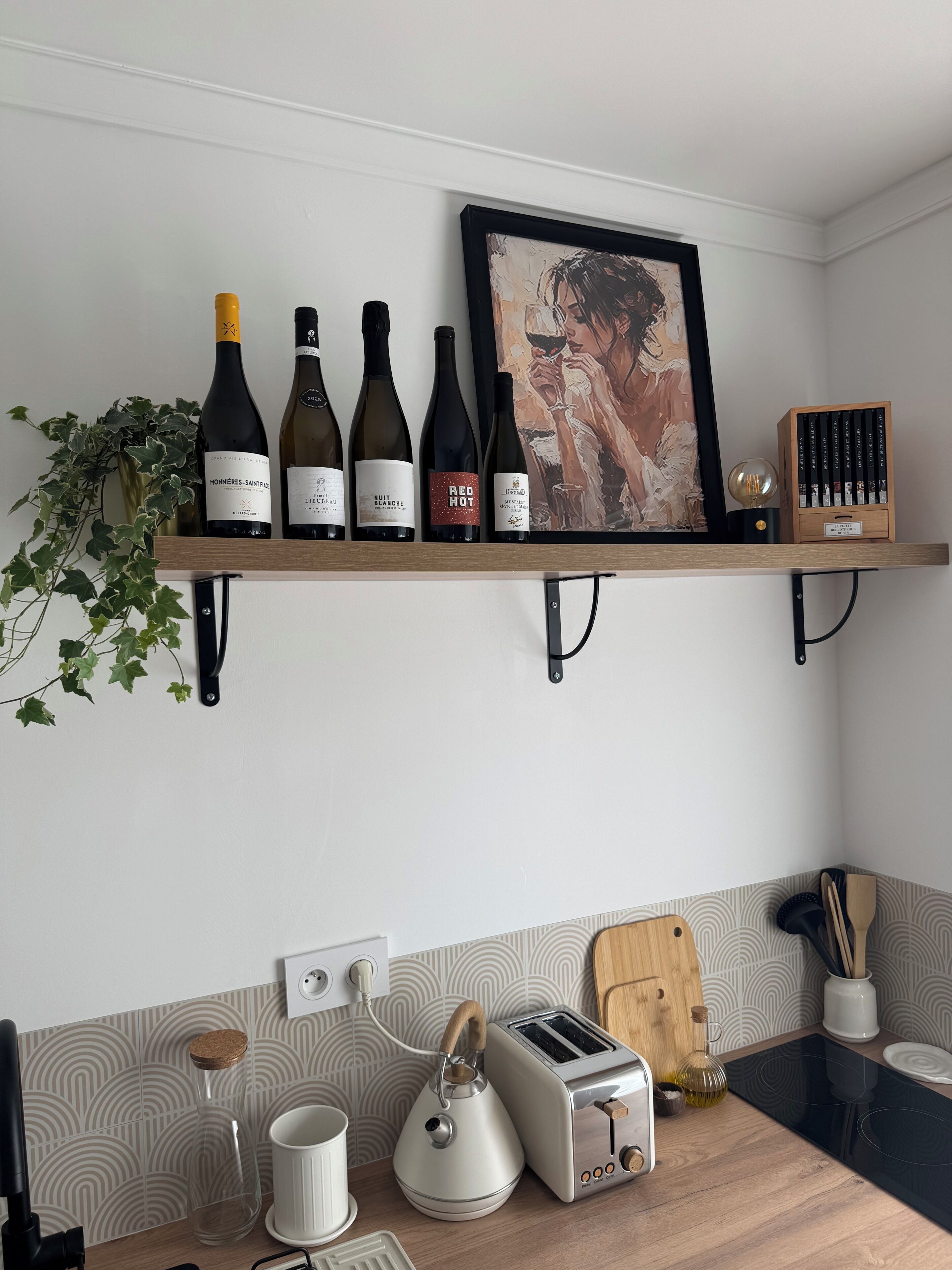 A kitchen with a wine rack, a framed artwork, and a wooden cutting board.