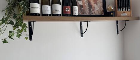 A kitchen with a wine rack, a framed artwork, and a wooden cutting board.