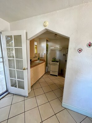 A kitchen with a stove, a sink, and a window with blinds. - Sunny Garden Hideaway in Historic Tucson Neighborhood (Tucson)