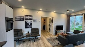 A modern living room with a sofa, chairs, a TV, and artwork on the wall. - Just Nature Miva 6 (Hindeloopen)