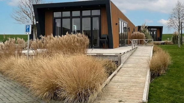 A modern building with a wooden deck, a parking sign, and a grassy area. - Just Nature Miva 6 (Hindeloopen)