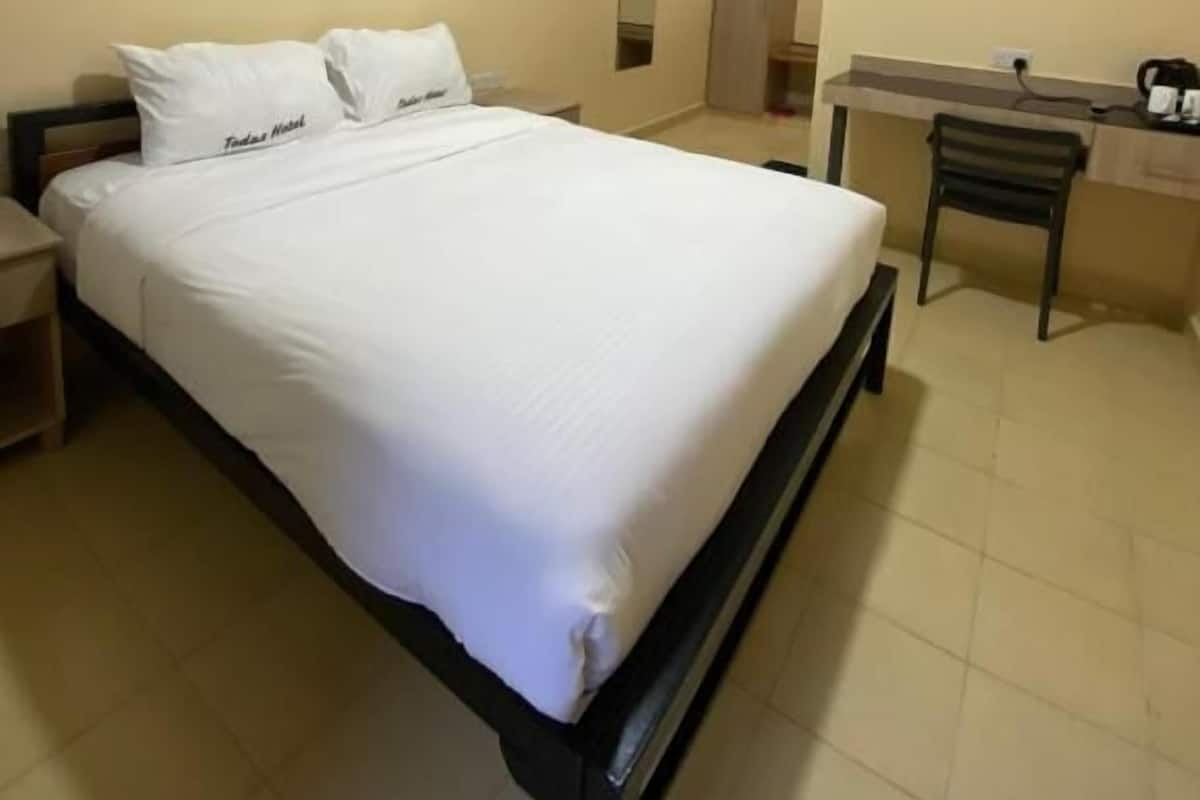A hotel room with a bed, nightstands, a desk, and a chair.