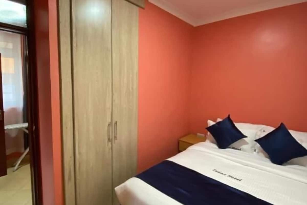 A bedroom with a bed, a wardrobe, and a nightstand.