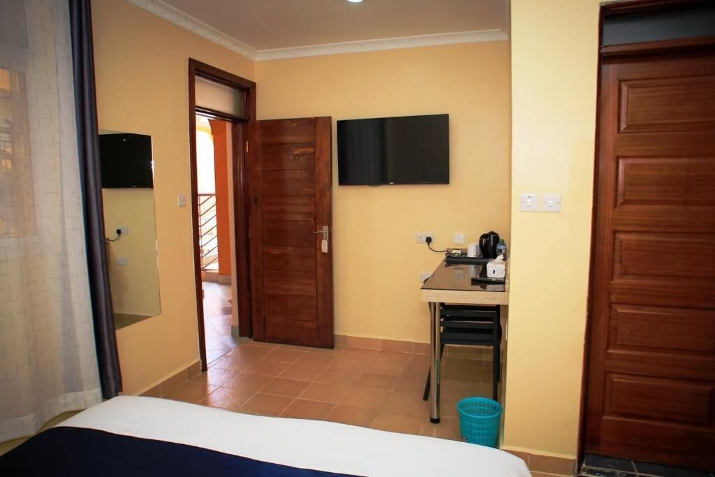 Une chambre d’hôtel avec un lit, un bureau équipé d’un ordinateur, une télévision et une porte donnant sur un balcon.