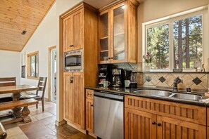 Una cocina con armarios de madera, microondas, cafetera y lavavajillas.