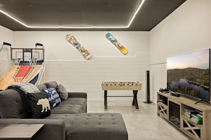 Una sala de estar moderna con una mesa de fútbol de mesa, un televisor y un aro de baloncesto.