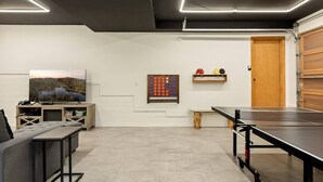 Et moderne værelse med et pingpongbord, et fjernsyn og et billede på væggen.