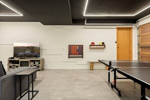 A modern room with a ping pong table, a TV, and a painting on the wall. - Snowboard Shores| Game Room | Hot Tub | Lake View (Big Bear Lake)
