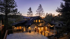 A modern house with a large deck, multiple windows, and a sloped roof. - Pine & Paw | Hot Tub, Sauna, Games, Views, Piano (Big Bear Lake)